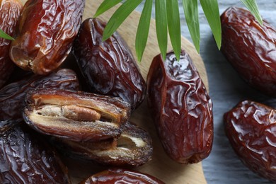 Photo of Many tasty dried dates and leaf on blue table, top view