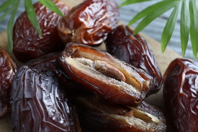 Photo of Many tasty dried dates and leaves on table, closeup