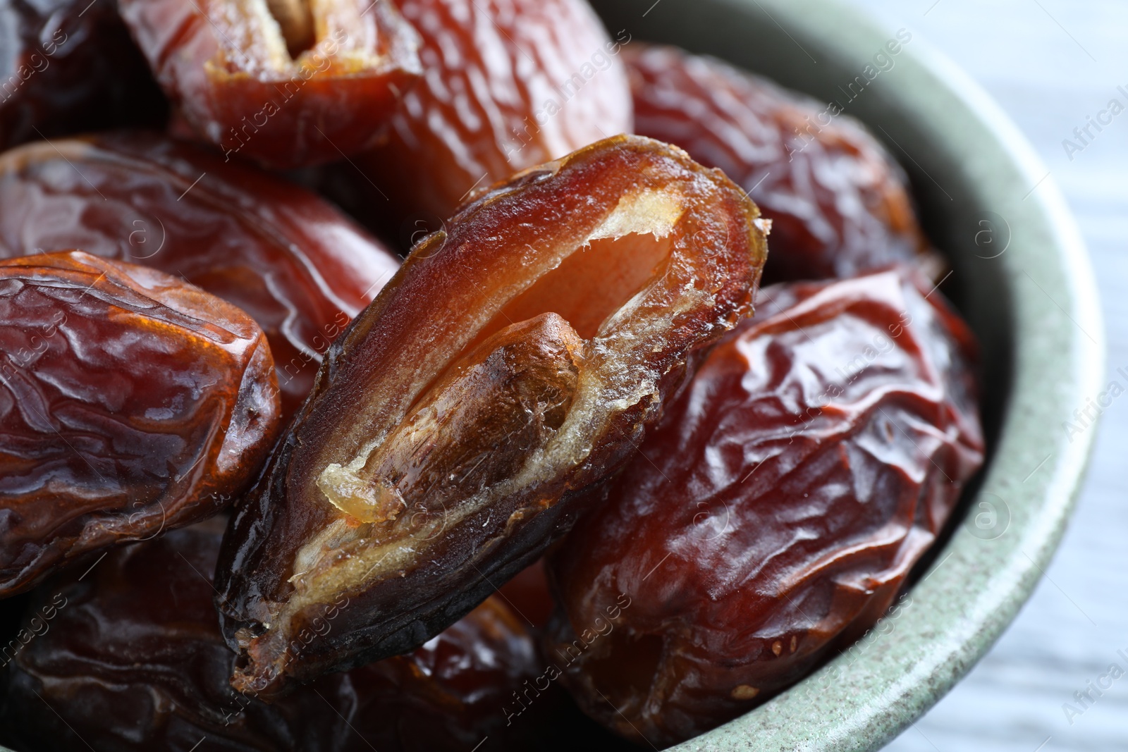 Photo of Many tasty dried dates in bowl on table, closeup