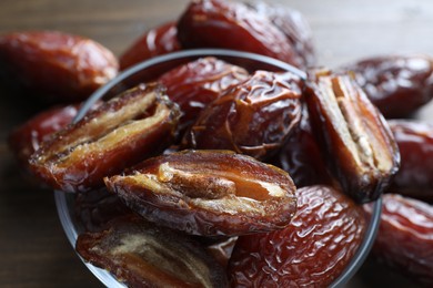 Photo of Many tasty dried dates in bowl on brown table, closeup