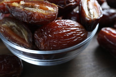 Photo of Many tasty dried dates in bowl on table, closeup