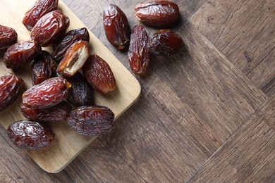 Photo of Many tasty dried dates on wooden table, top view. Space for text