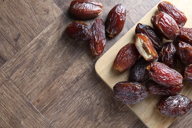 Photo of Many tasty dried dates on wooden table, top view. Space for text