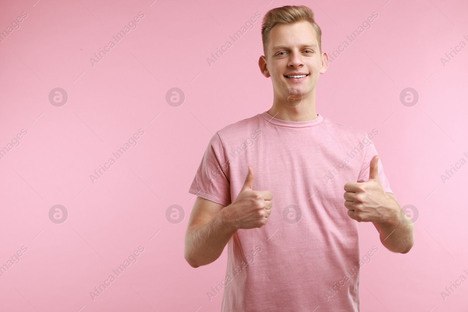 Photo of Happy man showing thumbs up on pink background, space for text. Like gesture