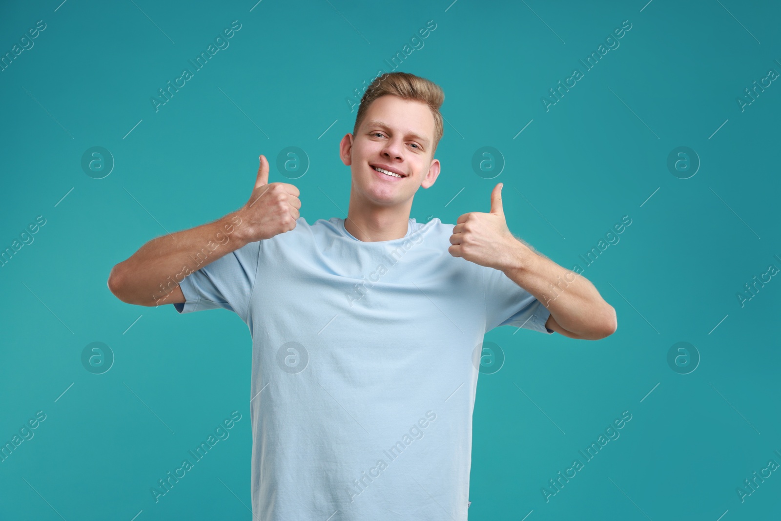 Photo of Happy man showing thumbs up on light blue background. Like gesture