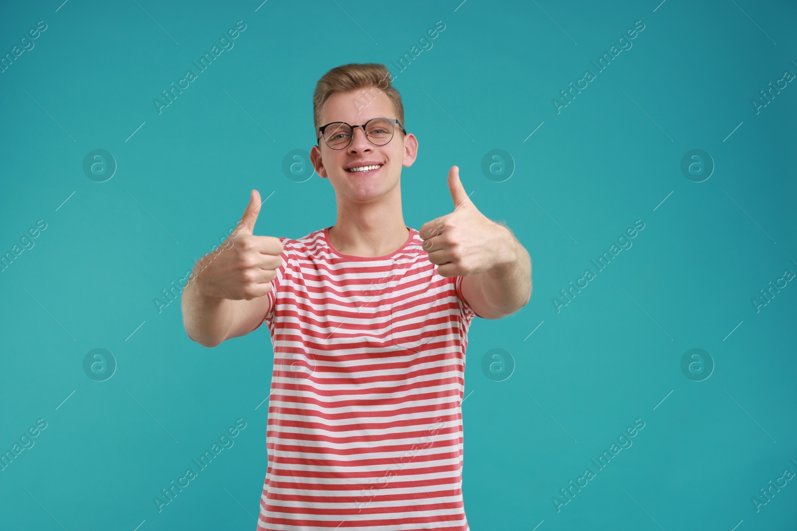 Photo of Happy man showing thumbs up on light blue background. Like gesture