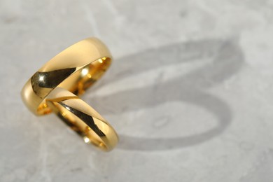 Photo of Beautiful golden wedding rings on gray background, top view. Space for text