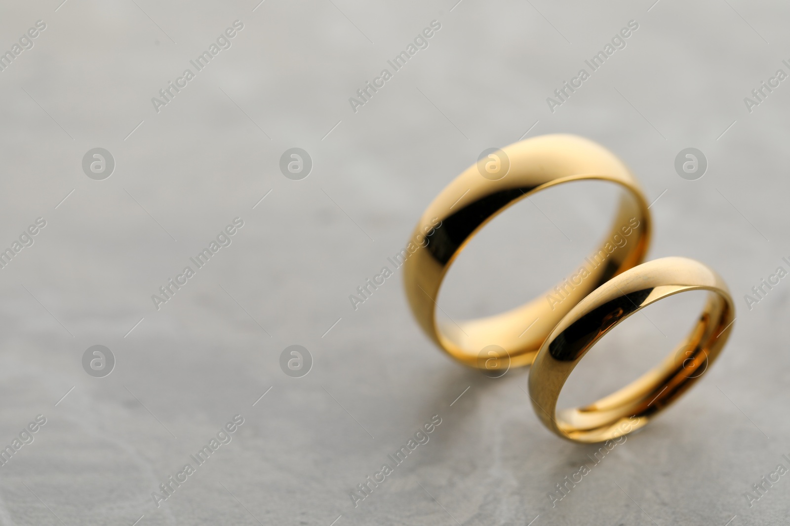 Photo of Beautiful golden wedding rings on gray background, closeup. Space for text