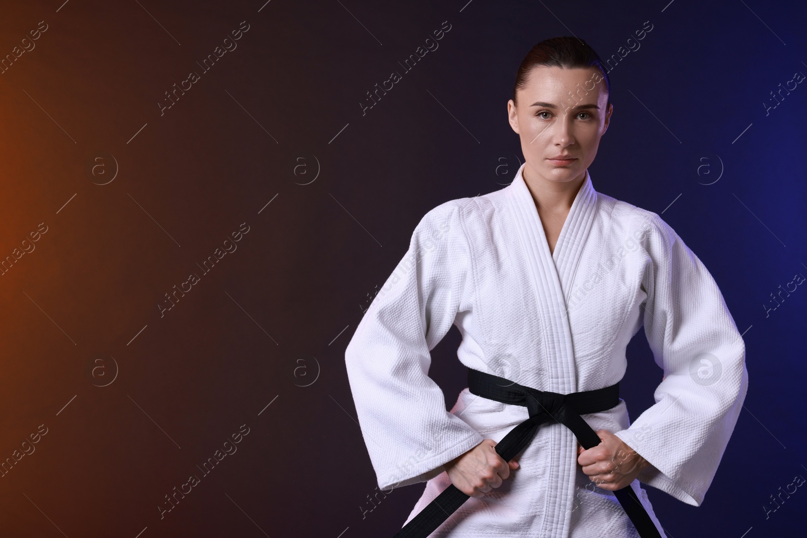 Photo of Karate fighter in kimono on color background, space for text