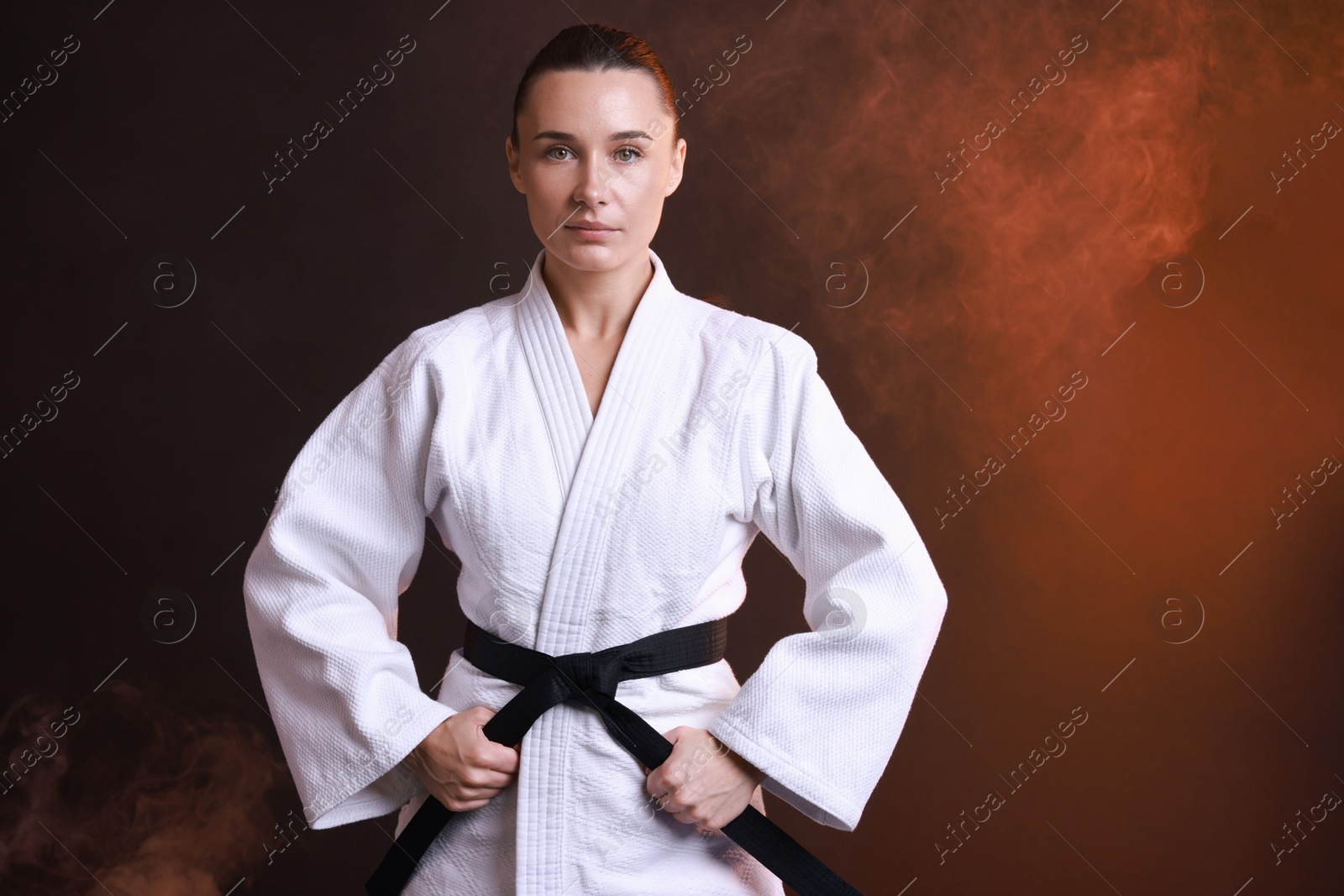 Photo of Young woman in kimono practicing karate on dark background