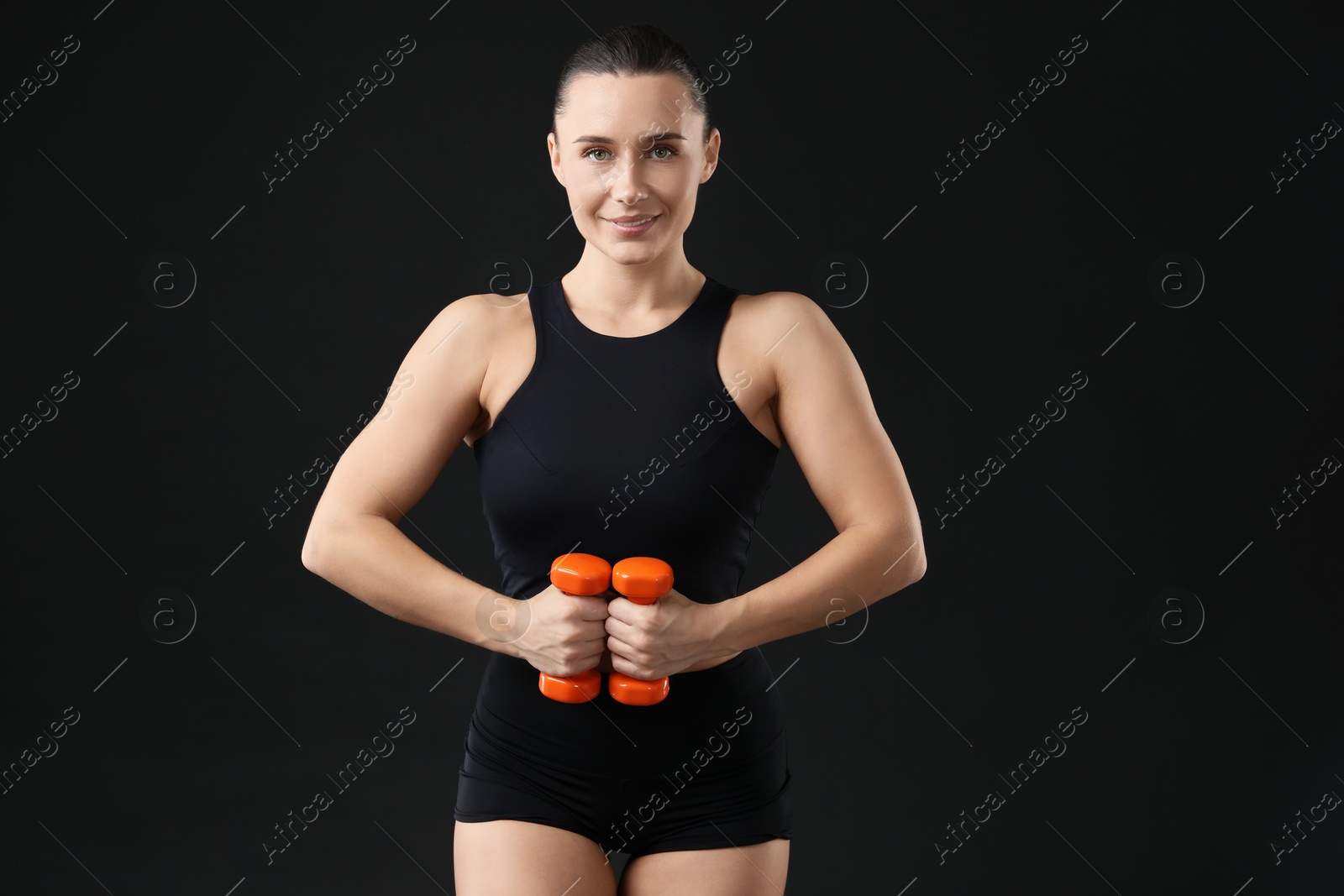 Photo of Woman exercising with dumbbells on black background