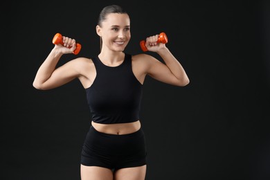 Photo of Woman exercising with dumbbells on black background