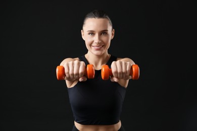 Photo of Woman exercising with dumbbells on black background