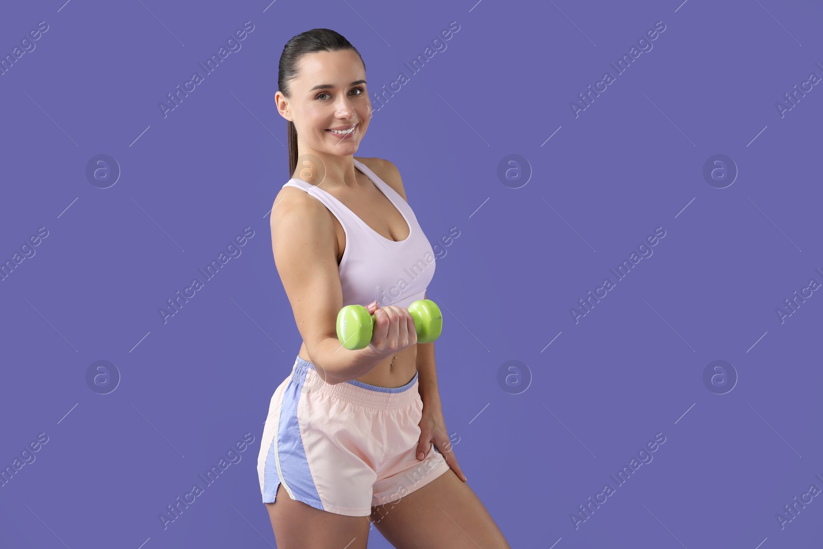 Photo of Woman exercising with dumbbell on purple background, space for text