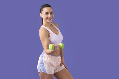 Woman exercising with dumbbell on purple background, space for text