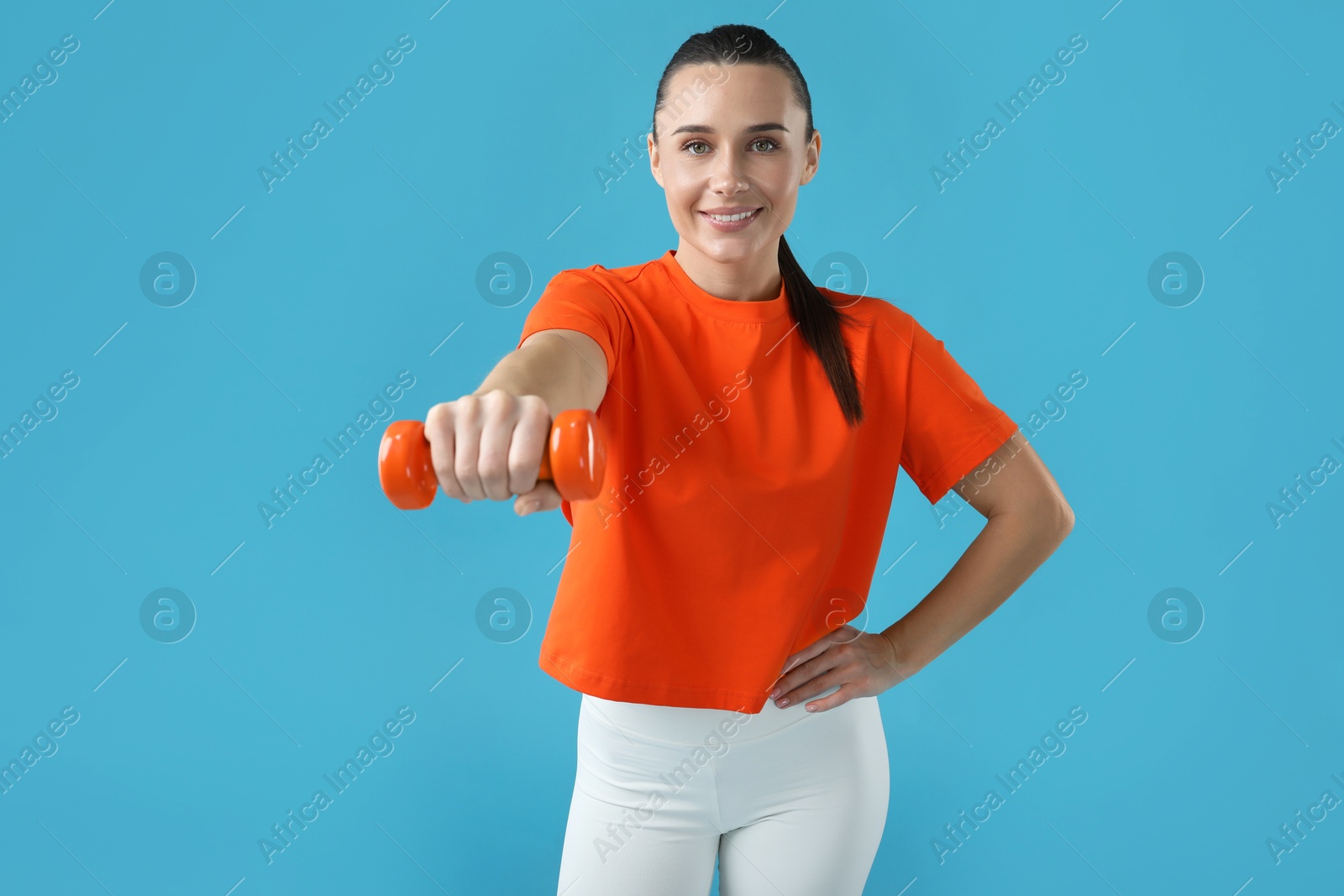 Photo of Woman exercising with dumbbells on light blue background