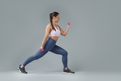 Photo of Woman exercising with dumbbells on light grey background, space for text