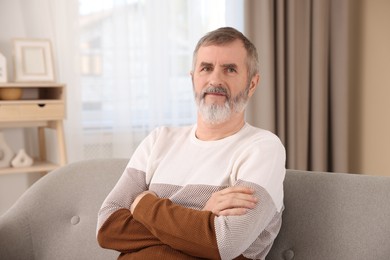 Photo of Mature man with crossed arms on sofa at home