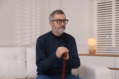 Photo of Mature man with walking cane at home