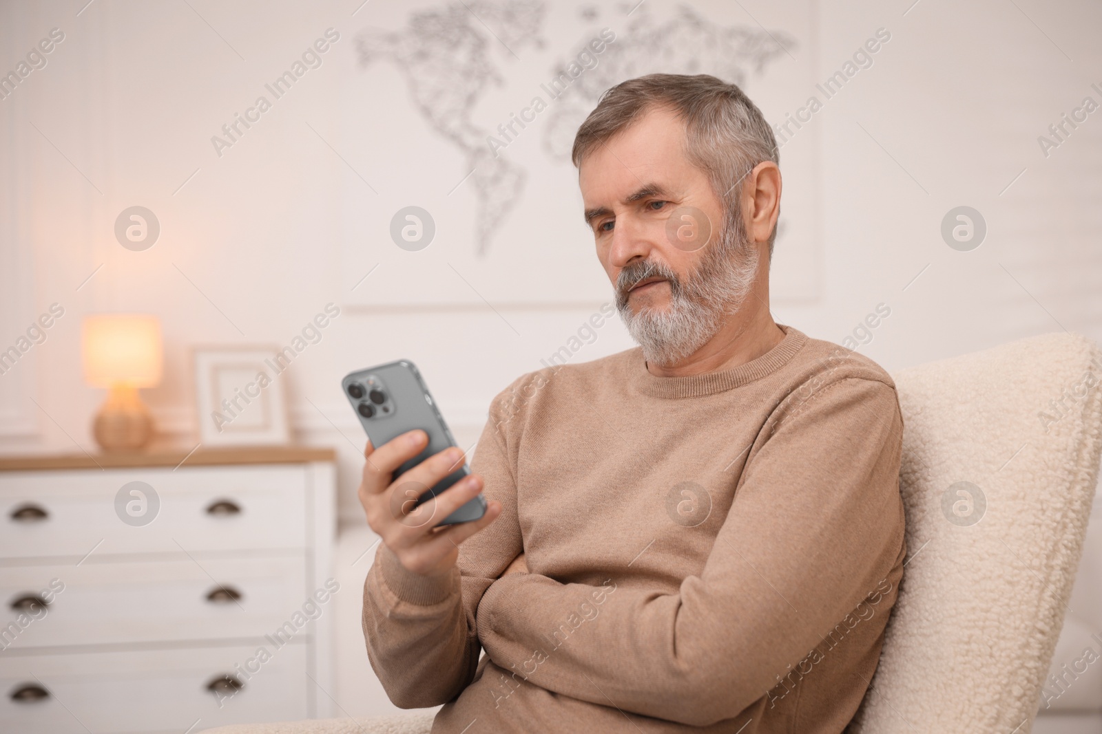 Photo of Mature man with smartphone at home. Space for text