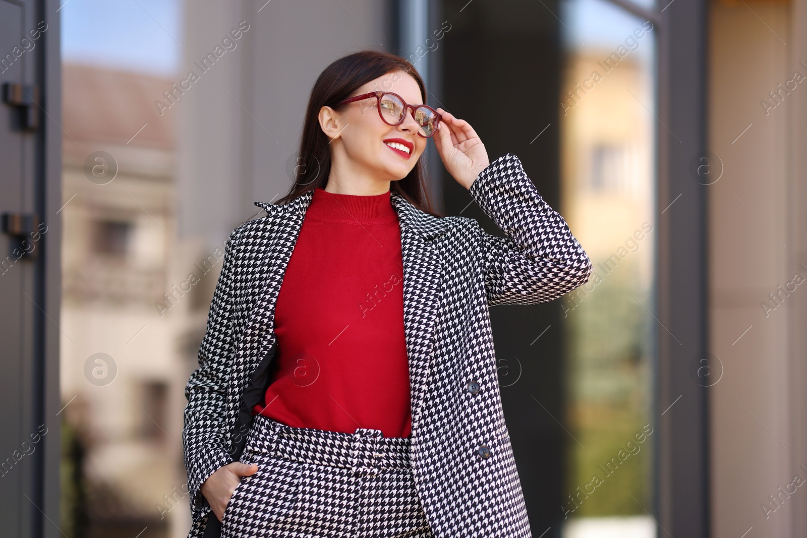 Photo of Smiling businesswoman in stylish suit outdoors, low angle view