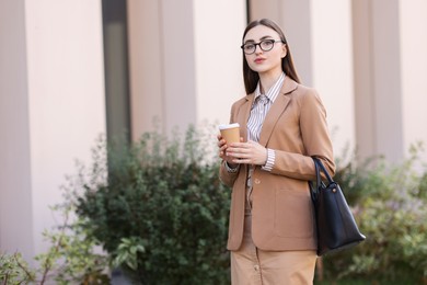 Photo of Businesswoman in stylish suit with paper cup outdoors. Space for text