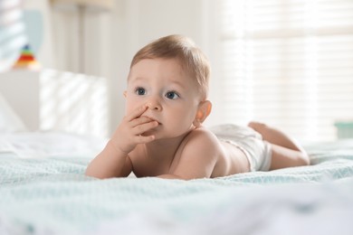 Photo of Cute little baby in diaper on bed at home