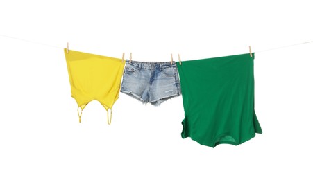 Different clothes drying on laundry line against white background