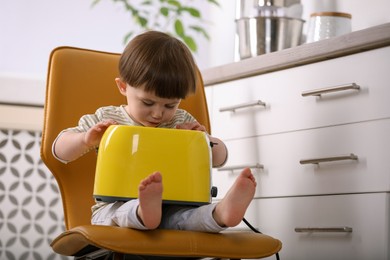 Little boy playing with toaster in kitchen. Dangerous situation