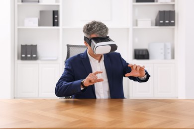 Photo of Man using virtual reality headset at desk in office