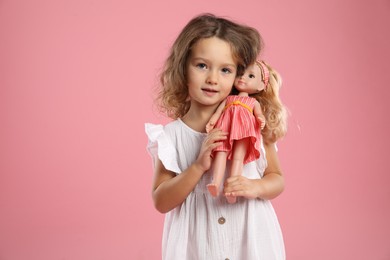 Photo of Cute little girl with doll on pink background