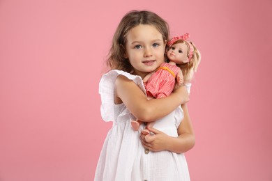 Photo of Cute little girl with doll on pink background