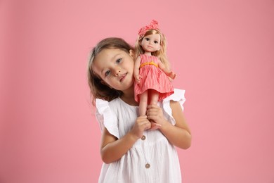 Photo of Cute little girl with doll on pink background