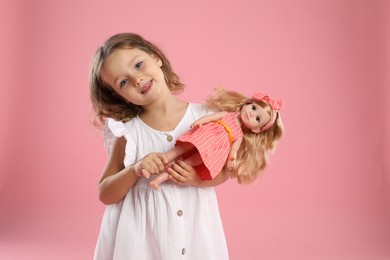 Photo of Cute little girl with doll on pink background