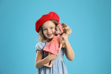 Photo of Cute little girl with doll on light blue background