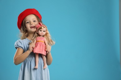 Photo of Cute little girl with doll on light blue background. Space for text