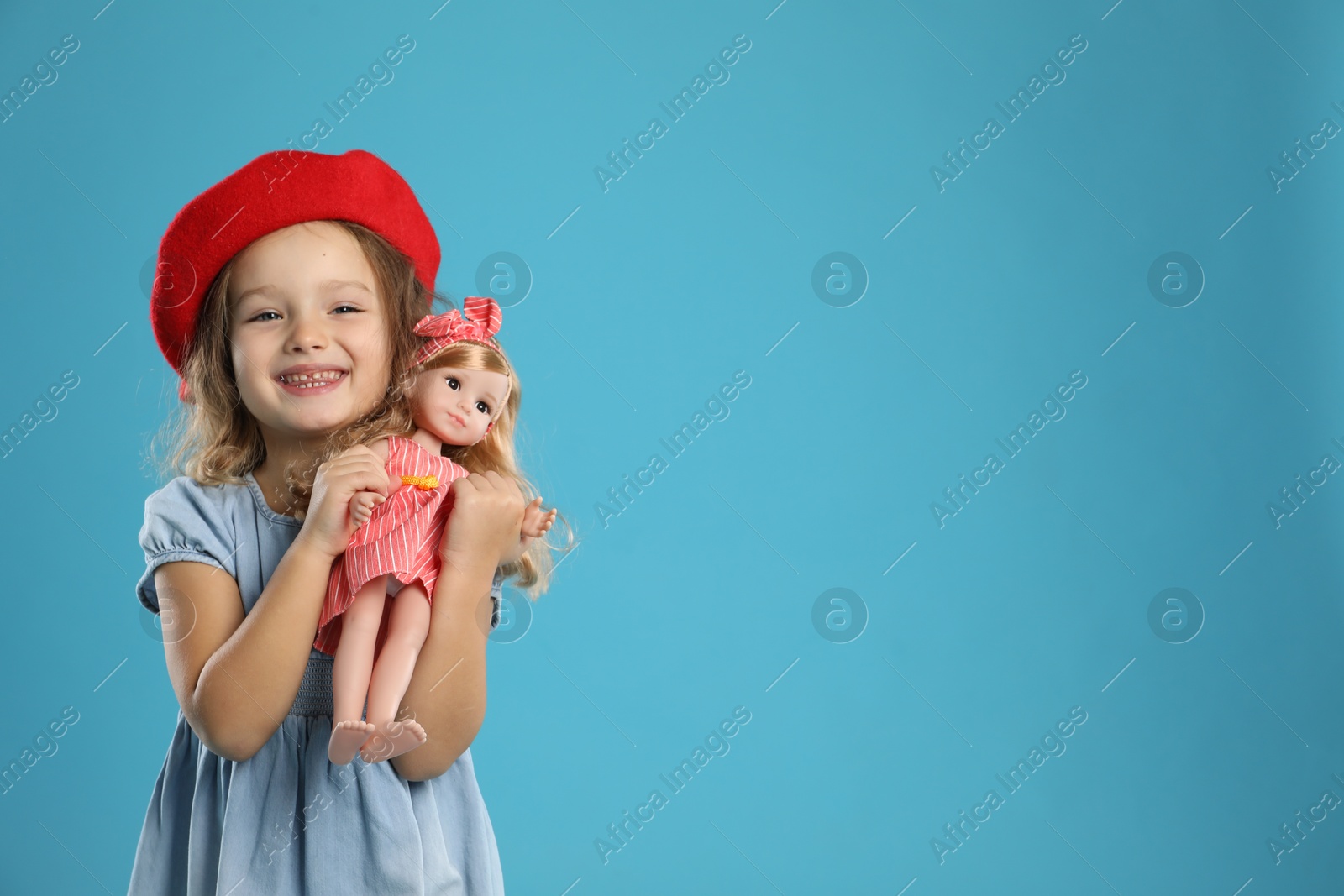 Photo of Cute little girl with doll on light blue background. Space for text