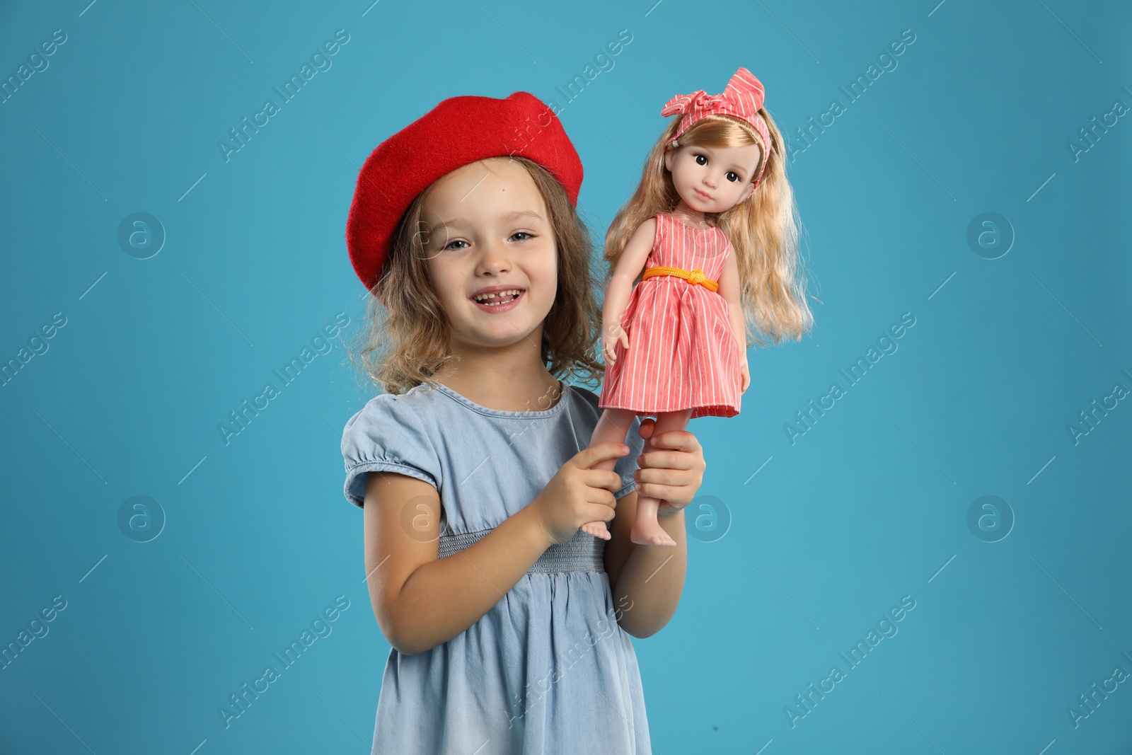 Photo of Cute little girl with doll on light blue background