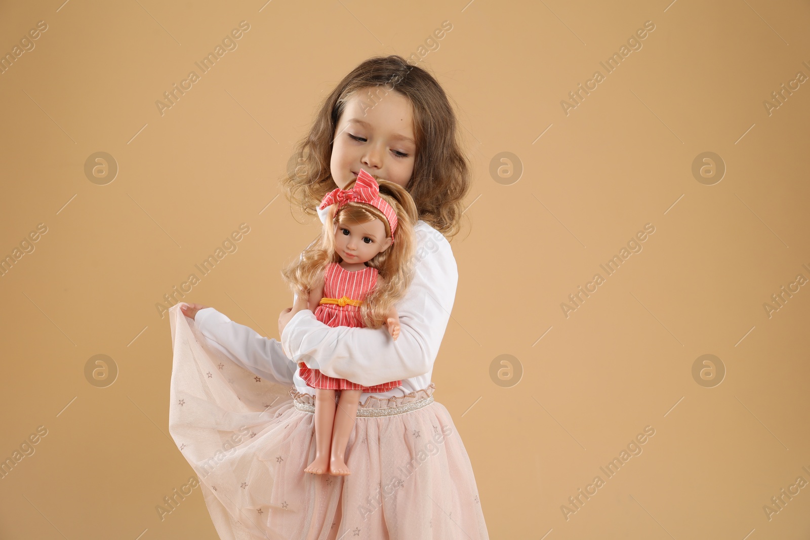 Photo of Cute little girl with doll on beige background. Space for text