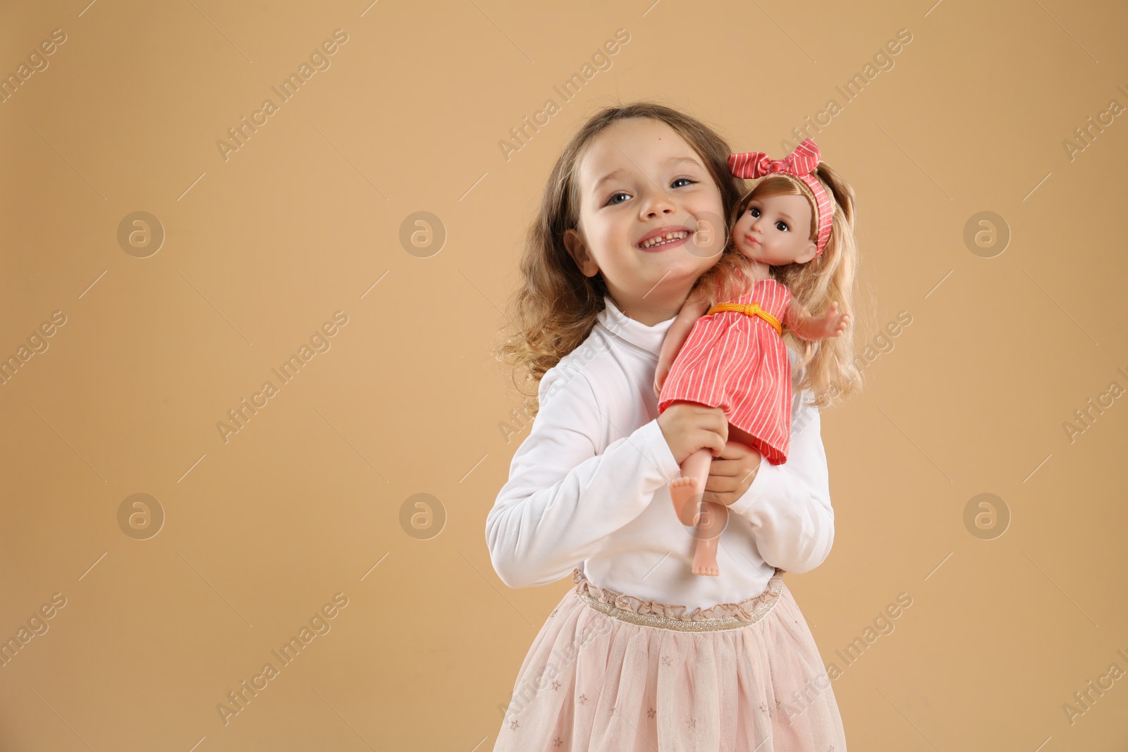 Photo of Cute little girl with doll on beige background. Space for text