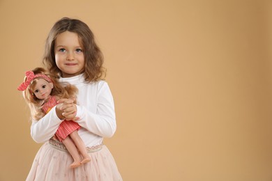 Photo of Cute little girl with doll on beige background. Space for text