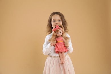 Photo of Cute little girl with doll on beige background