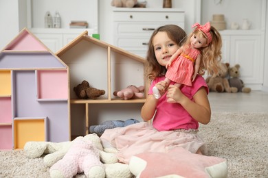 Photo of Cute little girl playing with her doll at home