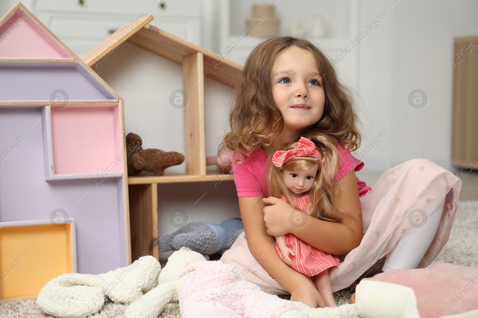 Photo of Cute little girl playing with her doll at home