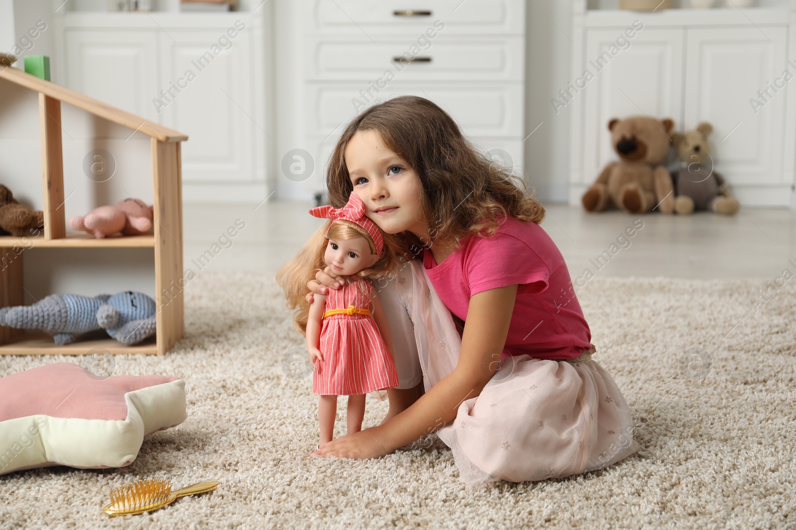 Photo of Cute little girl playing with her doll on floor at home