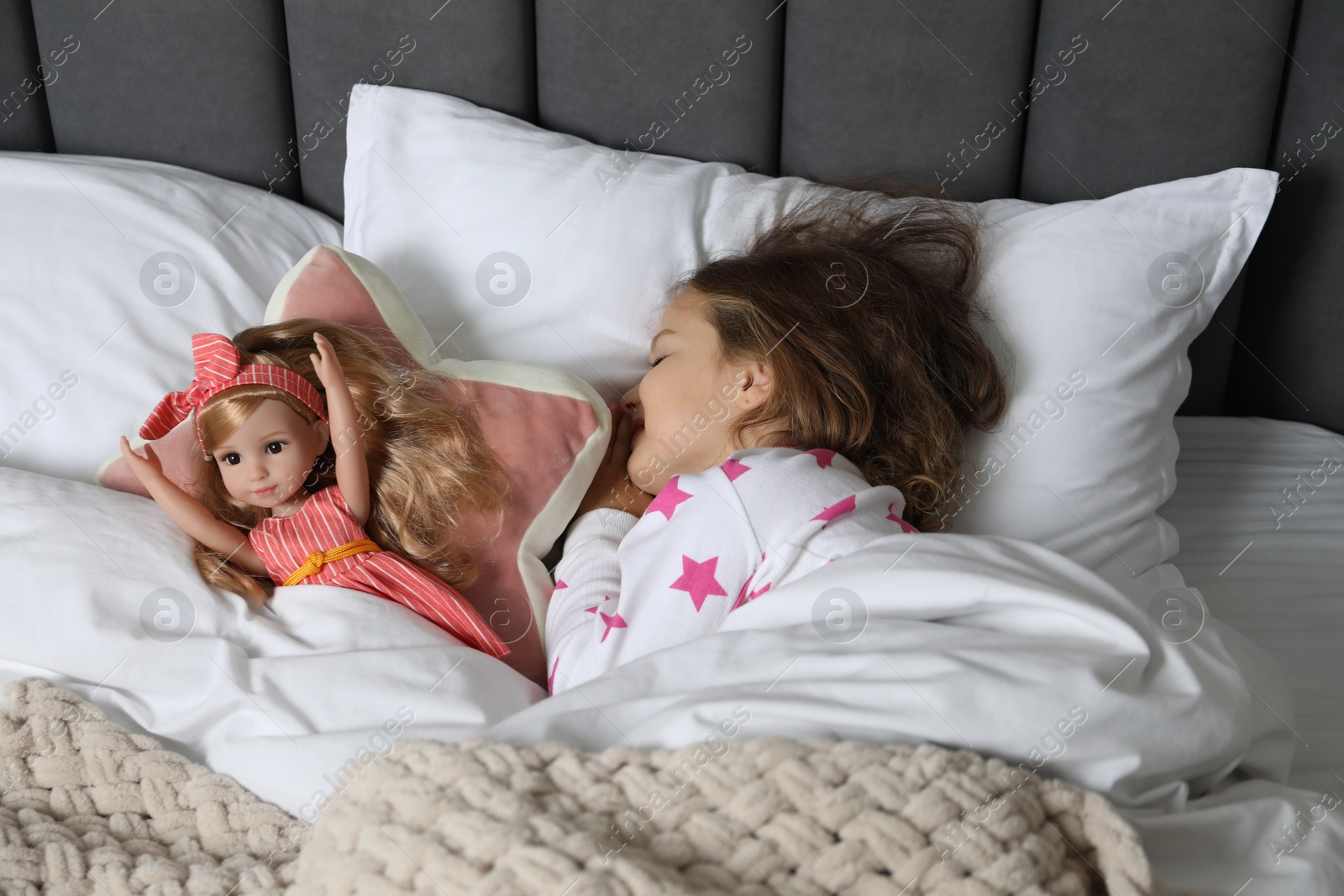 Photo of Little girl sleeping with doll in bed