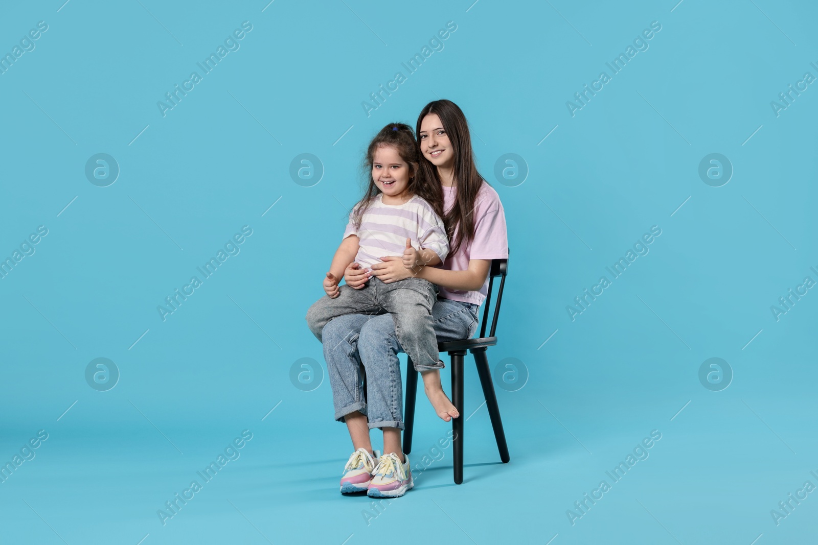 Photo of Portrait of cute sisters on light blue background