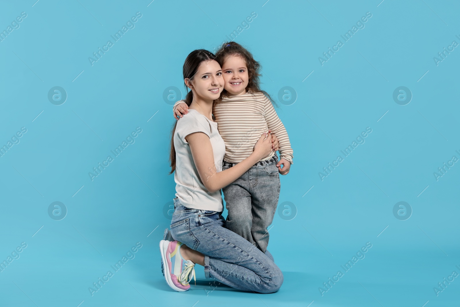 Photo of Portrait of cute sisters on light blue background