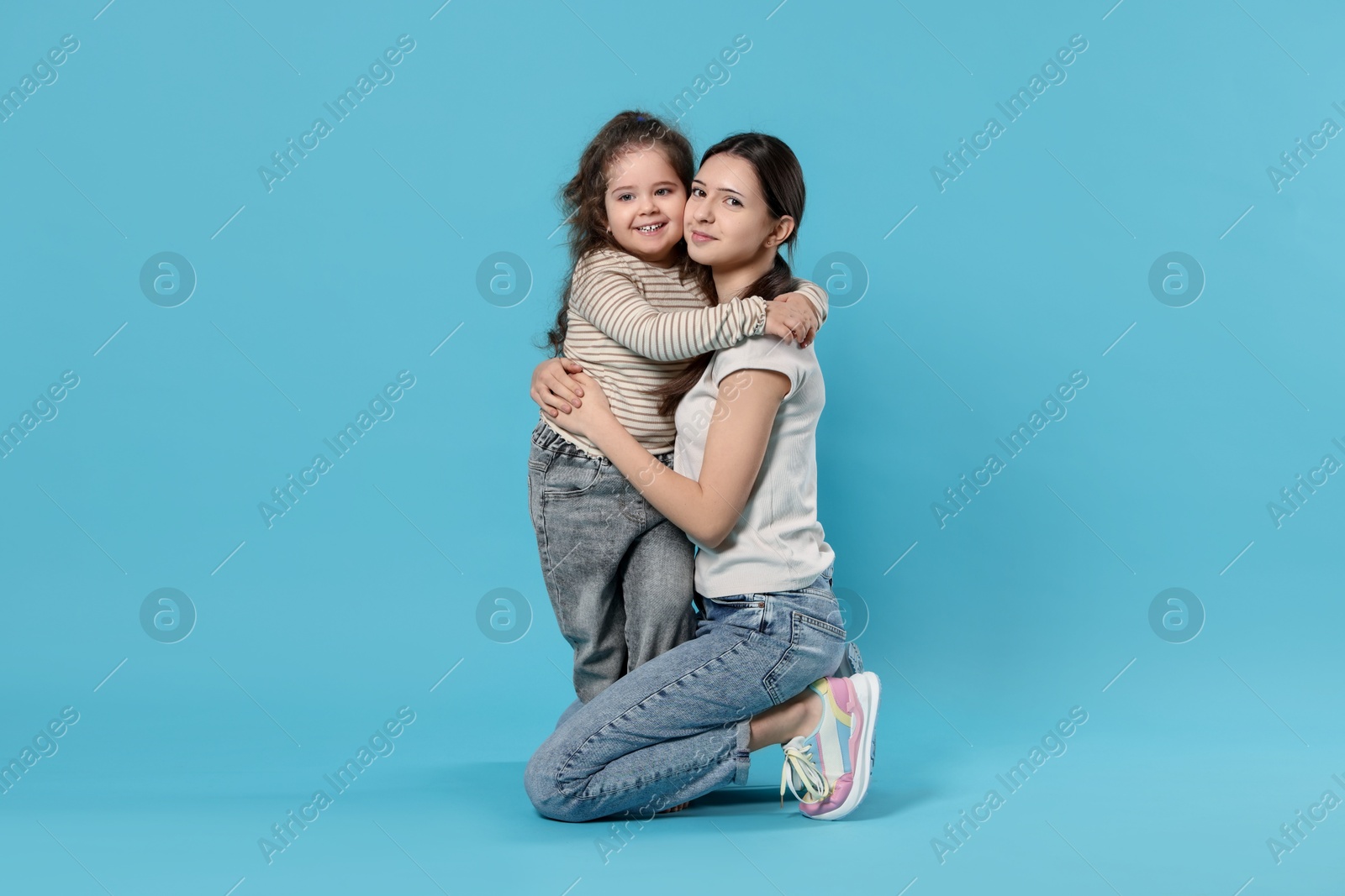 Photo of Portrait of cute sisters on light blue background