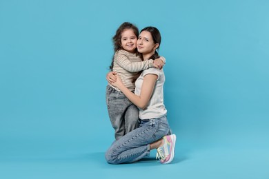 Photo of Portrait of cute sisters on light blue background